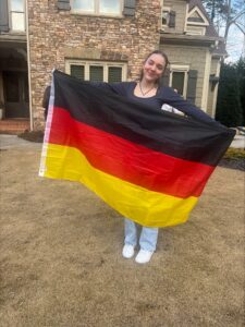 aya exchange student holding flag of germany in front of host family's house