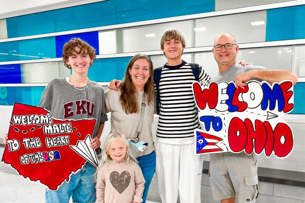 host family greeting aya exchange student at the airport with welcome signs