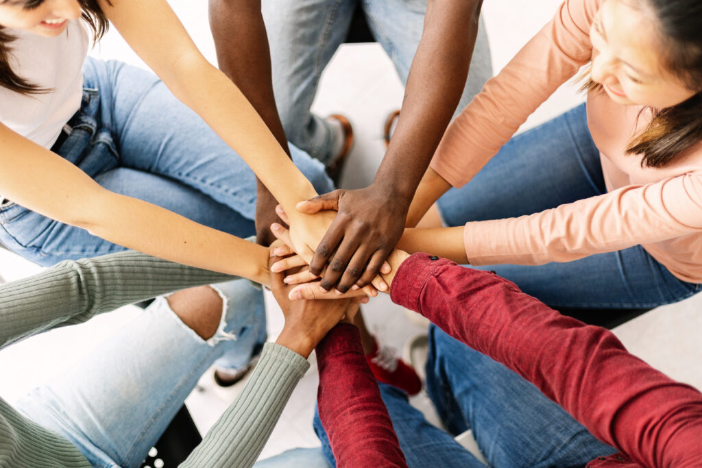 young friends people putting their hands together showing community, support, cooperation, unity and teamwork